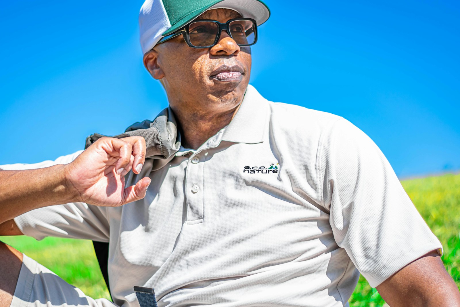 a man wearing a hat and glasses sitting in a field symbolizing how protecting your employees from hot weather benefits you