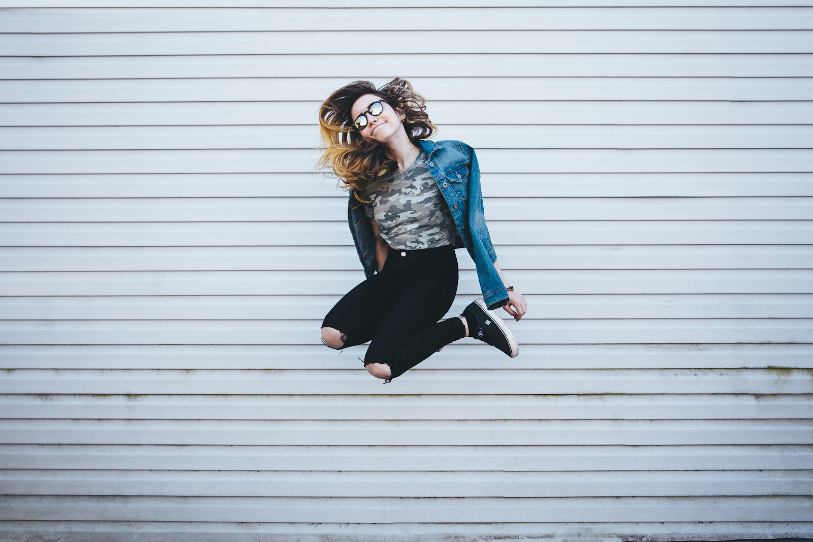 woman jumping in front of white concrete establishment symbolizing successful onboarding and how employee empowerment works