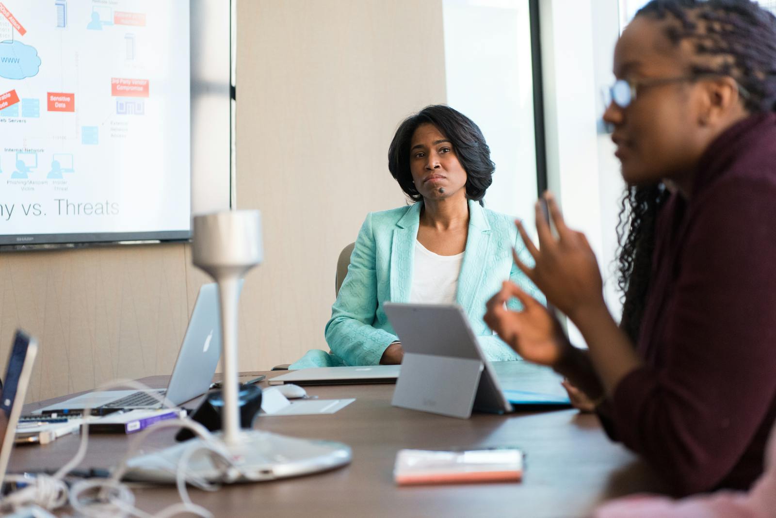 Professional women engaged in a business meeting, discussing strategy with technology at the workplace.